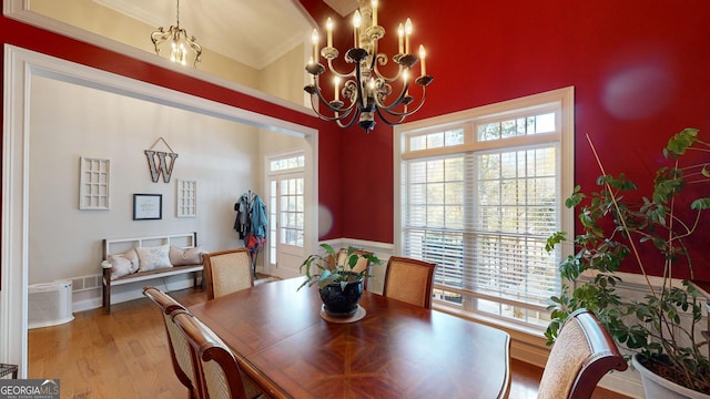 dining space featuring ornamental molding, a notable chandelier, and light wood-style flooring