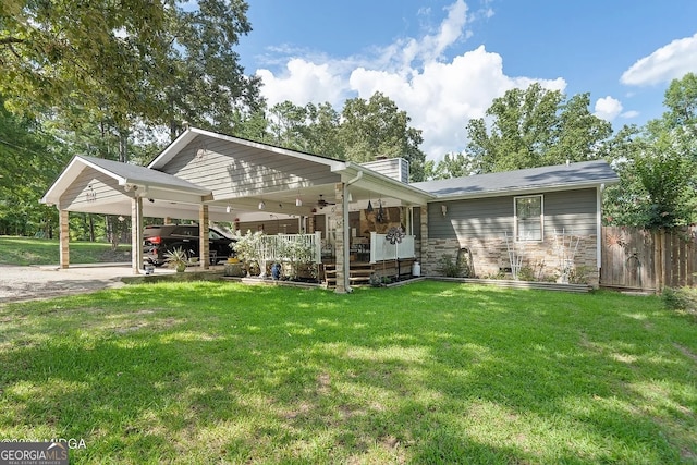 rear view of property featuring a yard, a carport, and ceiling fan