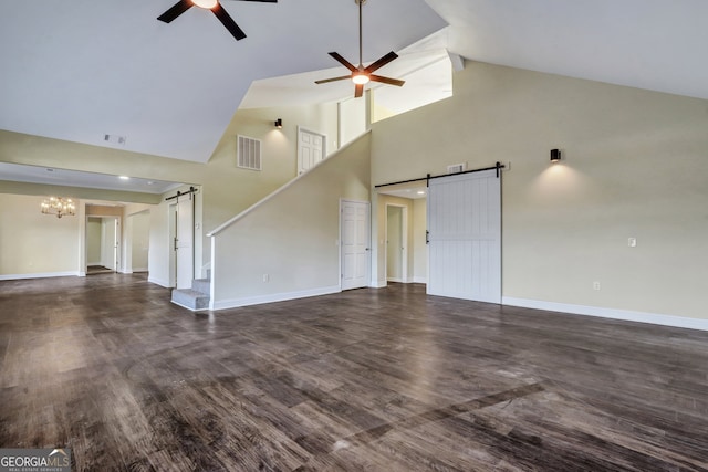 unfurnished living room with a barn door, high vaulted ceiling, and dark hardwood / wood-style flooring