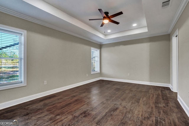 empty room with dark wood-type flooring, ceiling fan, a raised ceiling, and ornamental molding