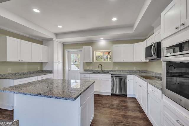 kitchen featuring white cabinets, stainless steel appliances, sink, and a kitchen island