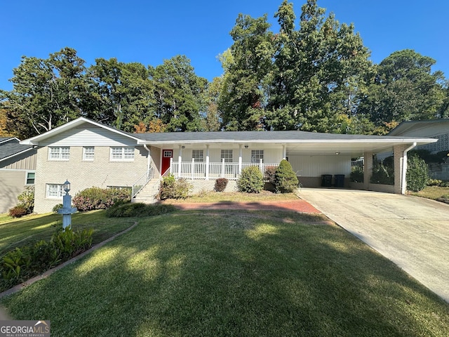 view of front of property with a porch, brick siding, a front lawn, concrete driveway, and an attached carport