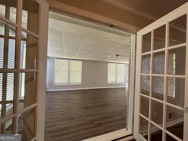 unfurnished room featuring baseboards, a paneled ceiling, and wood finished floors