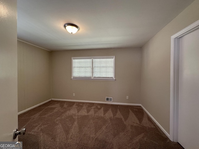 empty room featuring carpet floors, baseboards, and visible vents