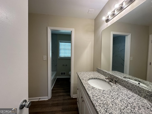 bathroom featuring visible vents, wood finished floors, vanity, baseboards, and toilet