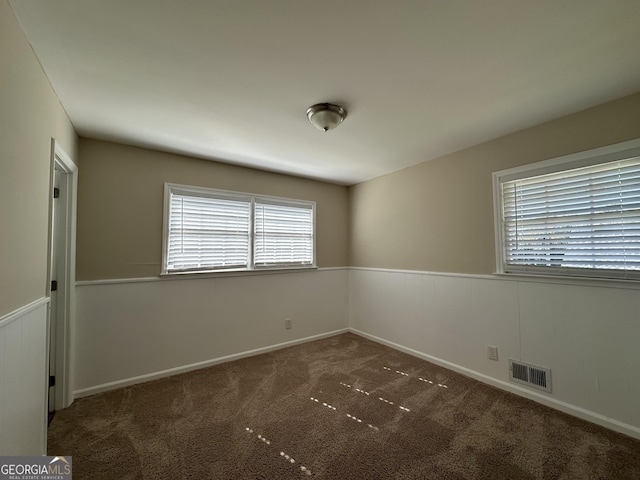 unfurnished room featuring carpet floors, baseboards, visible vents, and a healthy amount of sunlight