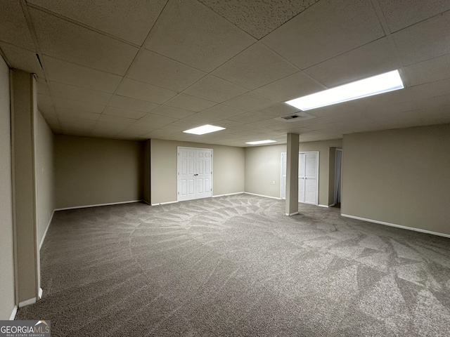 finished below grade area with baseboards, carpet flooring, a drop ceiling, and visible vents