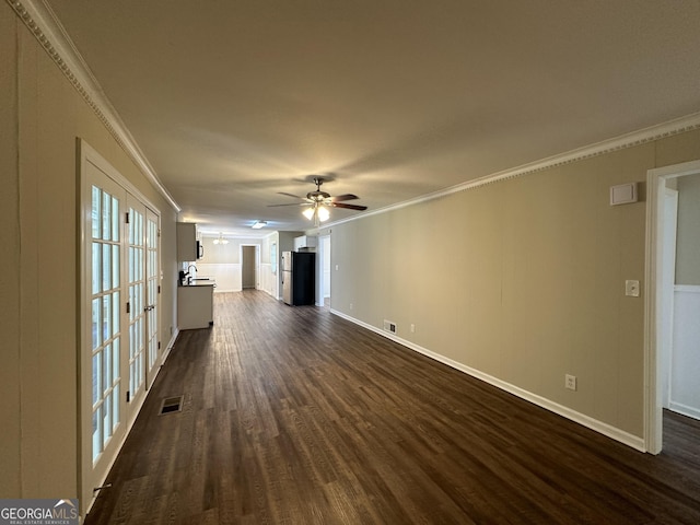 unfurnished living room with crown molding, baseboards, visible vents, and dark wood-type flooring