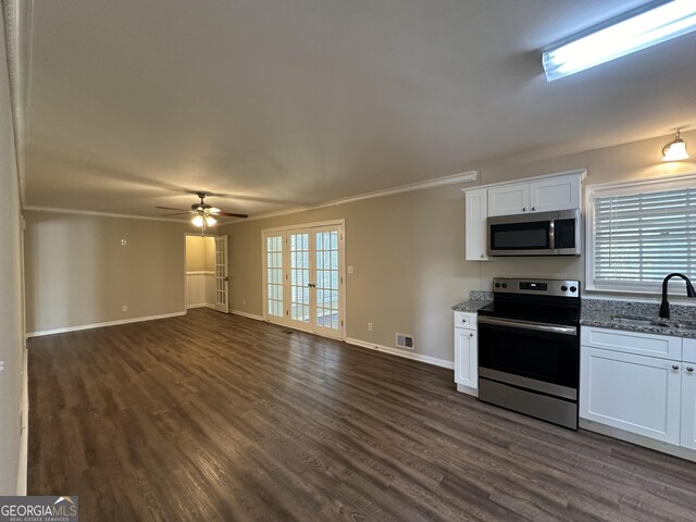 kitchen featuring appliances with stainless steel finishes, dark wood-style floors, a sink, and dark stone countertops