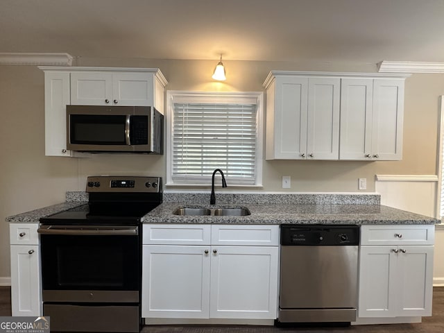 kitchen featuring white cabinets, stainless steel appliances, stone countertops, and a sink
