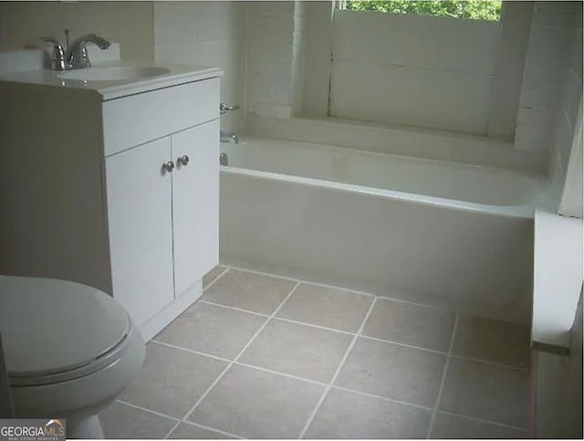 bathroom featuring vanity, a tub, tile patterned flooring, and toilet