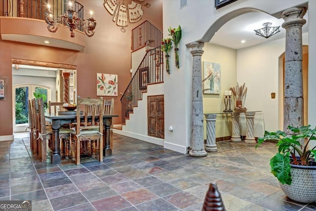 dining area featuring decorative columns, a towering ceiling, and french doors