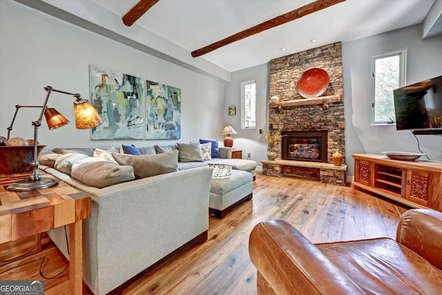 living room with a stone fireplace, beamed ceiling, and light wood-type flooring