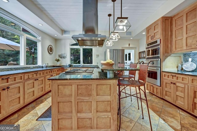 kitchen with island exhaust hood, hanging light fixtures, dark stone counters, a breakfast bar, and a center island