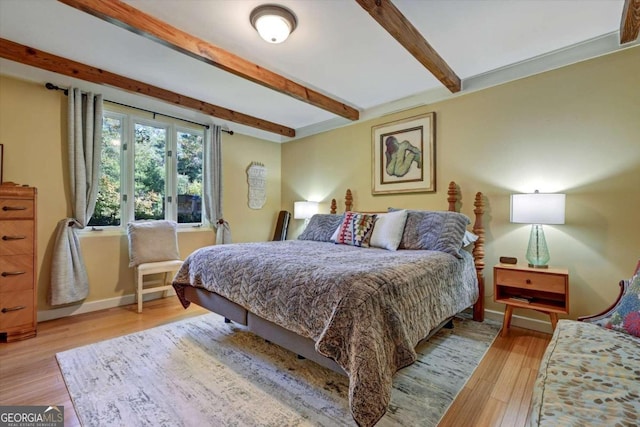 bedroom featuring beamed ceiling and light wood-type flooring