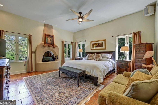 bedroom with multiple windows, a fireplace, and ceiling fan