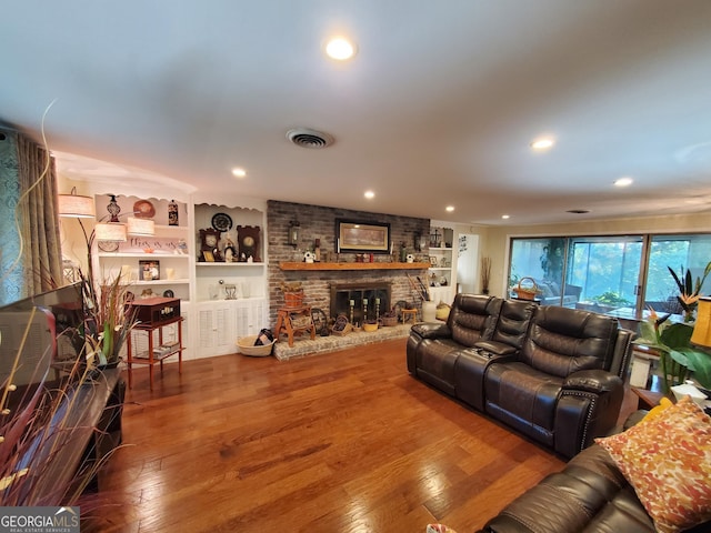 living area featuring recessed lighting, wood-type flooring, visible vents, and a fireplace