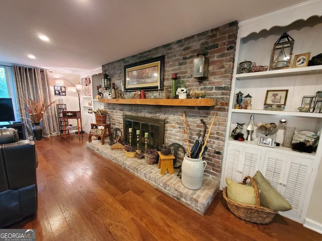 living area with hardwood / wood-style floors, a fireplace, and built in shelves