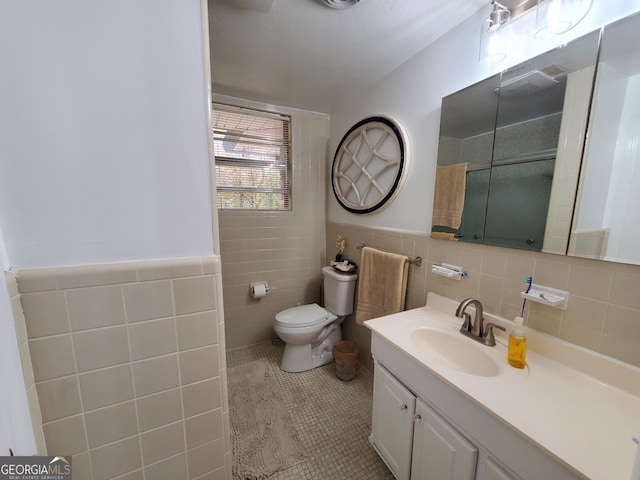 bathroom with toilet, tile patterned floors, walk in shower, vanity, and tile walls