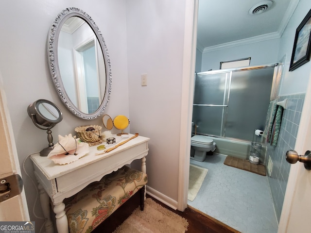 bathroom with toilet, bath / shower combo with glass door, and crown molding