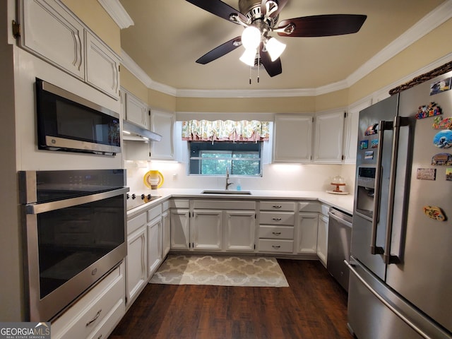 kitchen with dark wood-type flooring, stainless steel appliances, crown molding, light countertops, and a sink