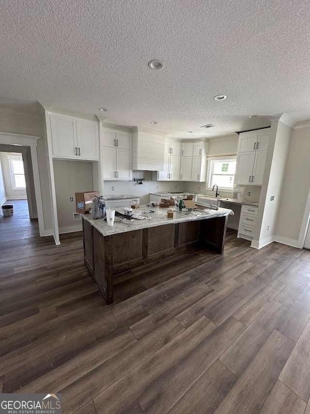 kitchen with white cabinets, baseboards, dark wood-style flooring, and a kitchen island