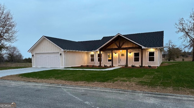 view of front facade featuring a front yard, roof with shingles, concrete driveway, and an attached garage