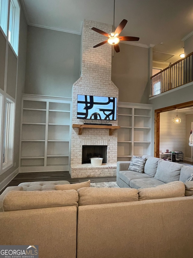 living room featuring a high ceiling, hardwood / wood-style flooring, crown molding, a brick fireplace, and ceiling fan