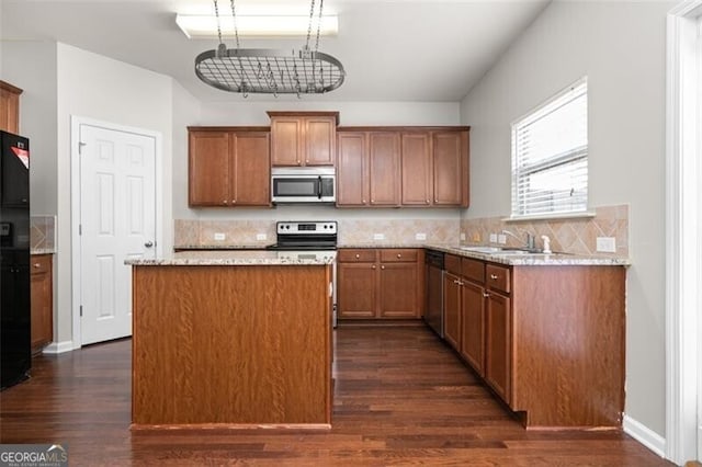 kitchen with appliances with stainless steel finishes, decorative backsplash, a center island, and dark hardwood / wood-style flooring