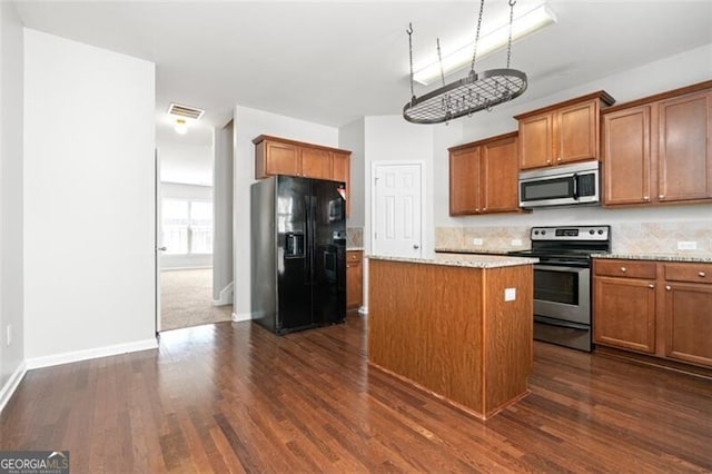 kitchen with a kitchen island, backsplash, stainless steel appliances, dark wood-type flooring, and light stone counters