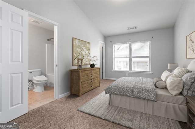 carpeted bedroom featuring lofted ceiling and ensuite bathroom