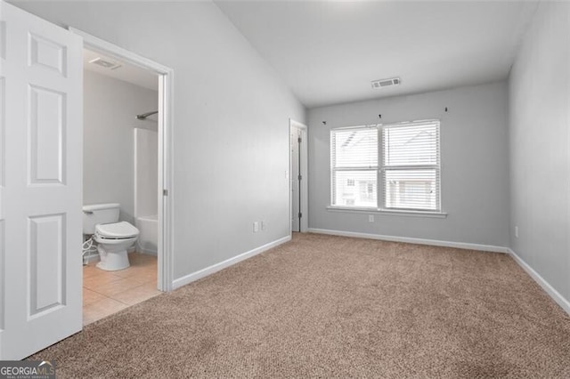 unfurnished bedroom with lofted ceiling, light colored carpet, and connected bathroom