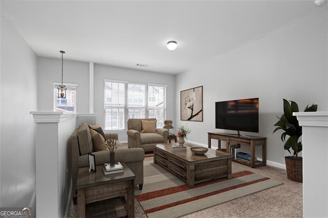 carpeted living room with a notable chandelier