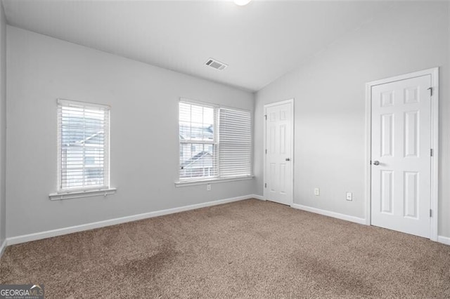 unfurnished bedroom with carpet, vaulted ceiling, and multiple windows