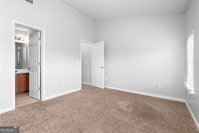 unfurnished bedroom featuring light carpet and ensuite bath