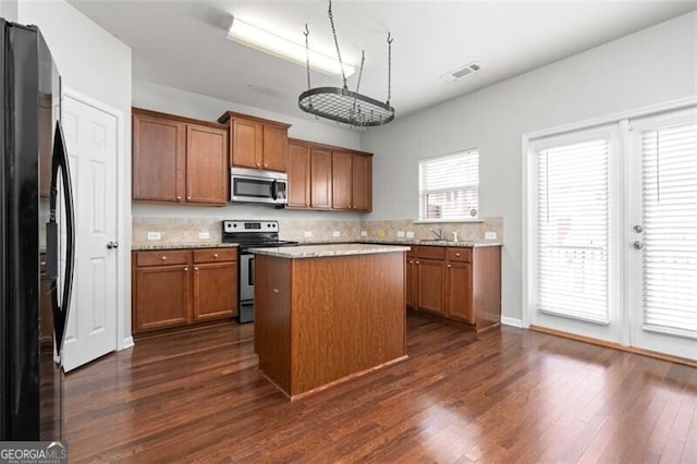 kitchen featuring tasteful backsplash, appliances with stainless steel finishes, a center island, and dark hardwood / wood-style flooring