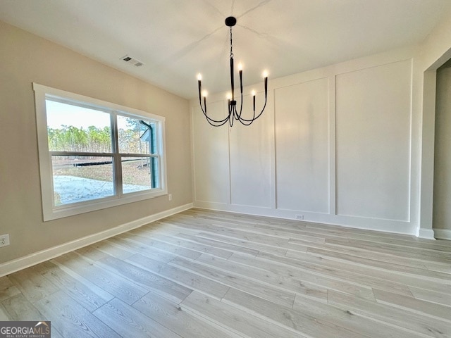 unfurnished dining area with light hardwood / wood-style flooring and a chandelier