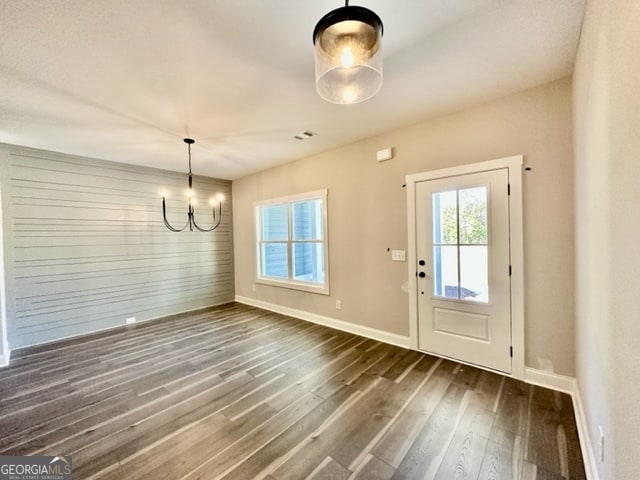 entryway with an inviting chandelier and dark wood-type flooring