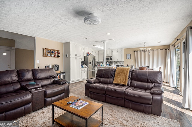 living room featuring dark hardwood / wood-style floors, a textured ceiling, and an inviting chandelier