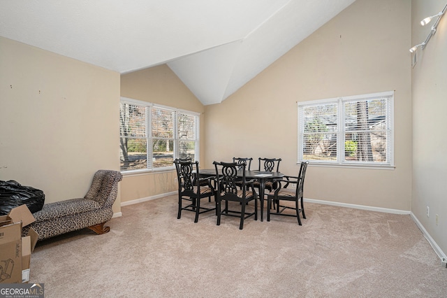 dining area featuring light colored carpet and vaulted ceiling