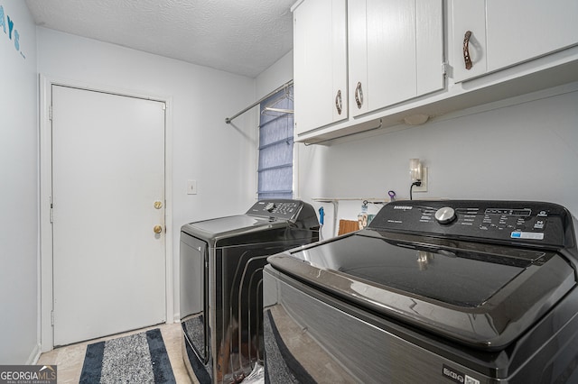 laundry room featuring cabinets, a textured ceiling, and washing machine and clothes dryer