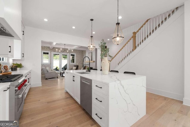 kitchen featuring open floor plan, appliances with stainless steel finishes, light wood-type flooring, and a sink