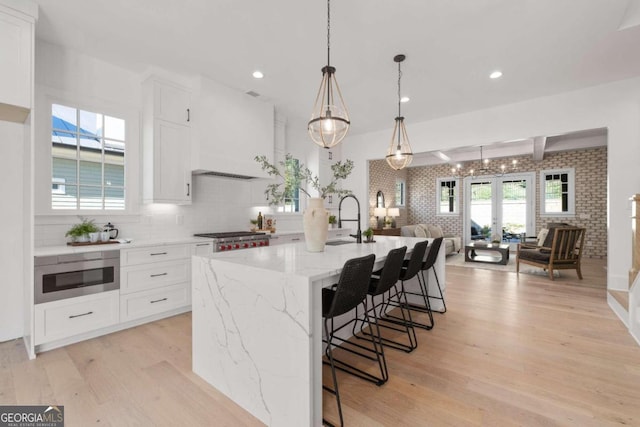 kitchen featuring light stone countertops, light wood-style flooring, white cabinetry, and stainless steel microwave