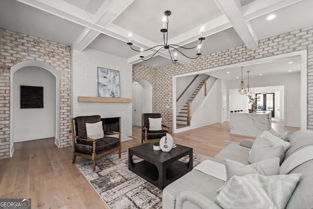 living area with arched walkways, light wood finished floors, and a chandelier