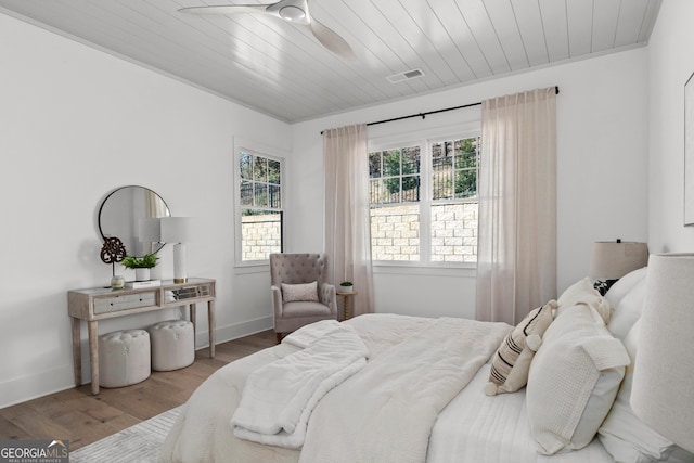 bedroom with wooden ceiling, baseboards, visible vents, and wood finished floors