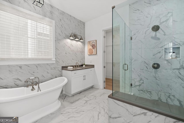 bathroom with a marble finish shower, a soaking tub, marble finish floor, vanity, and tile walls