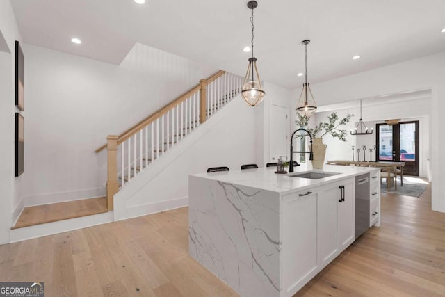 kitchen featuring a center island with sink, decorative light fixtures, light wood-type flooring, a sink, and recessed lighting