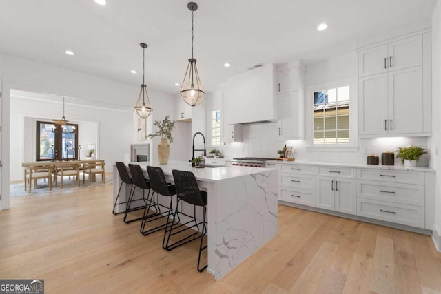 kitchen with a kitchen island with sink, plenty of natural light, and white cabinets