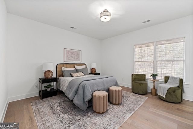 bedroom with baseboards, visible vents, and wood finished floors