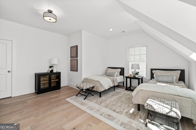 bedroom with vaulted ceiling, wood finished floors, visible vents, and baseboards